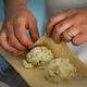 Person's hands folding knish